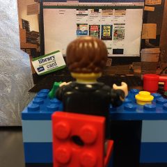 Lego figure sitting at a Lego Library computer