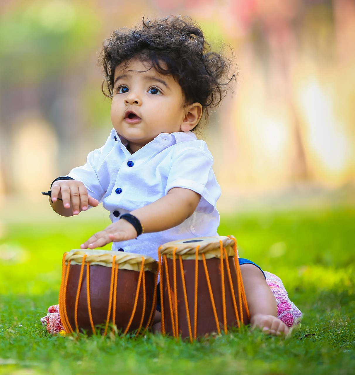 Baby is playing two drums with his hands