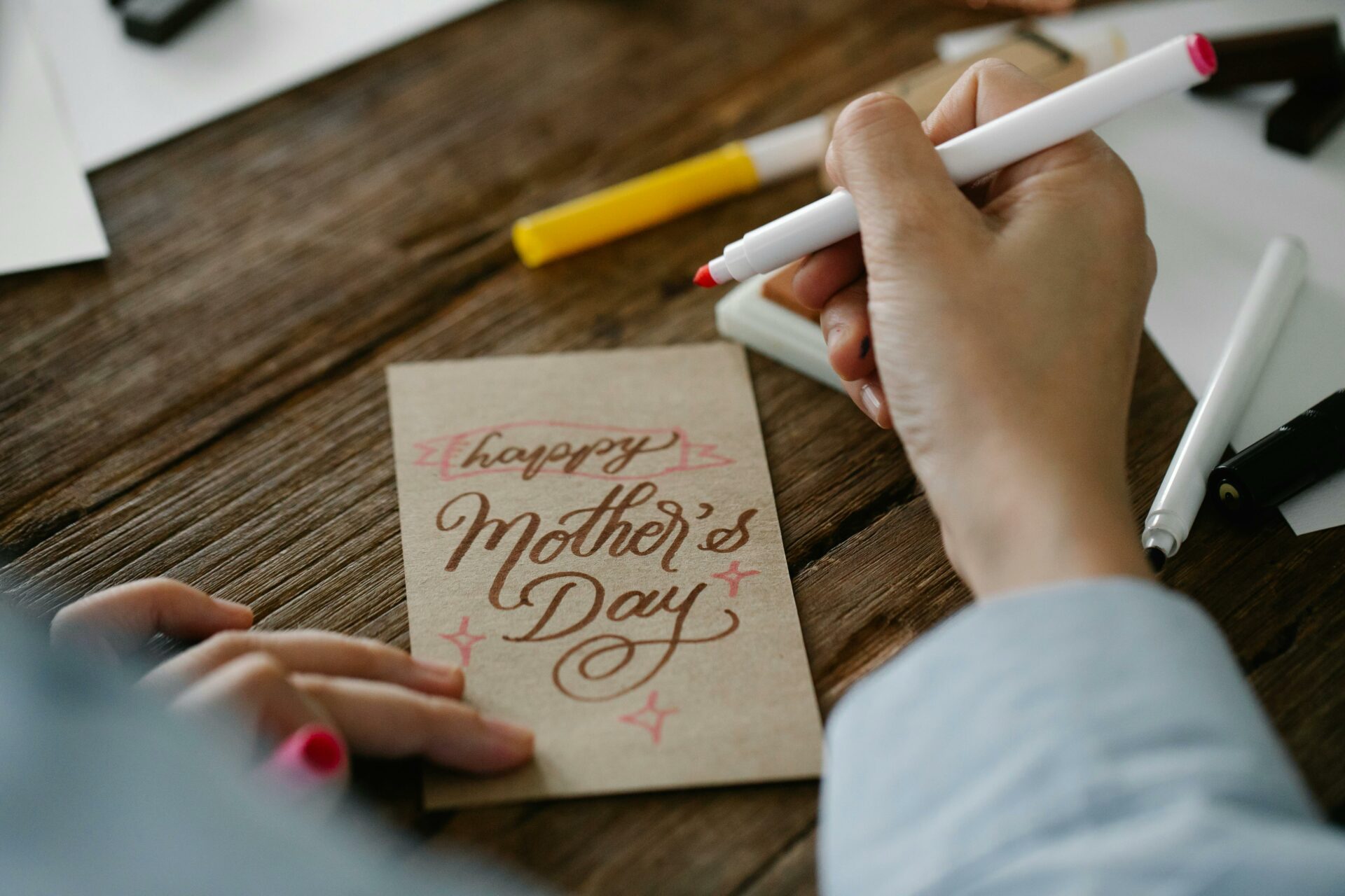 Adult hands holding a marker and making Mother's Day card