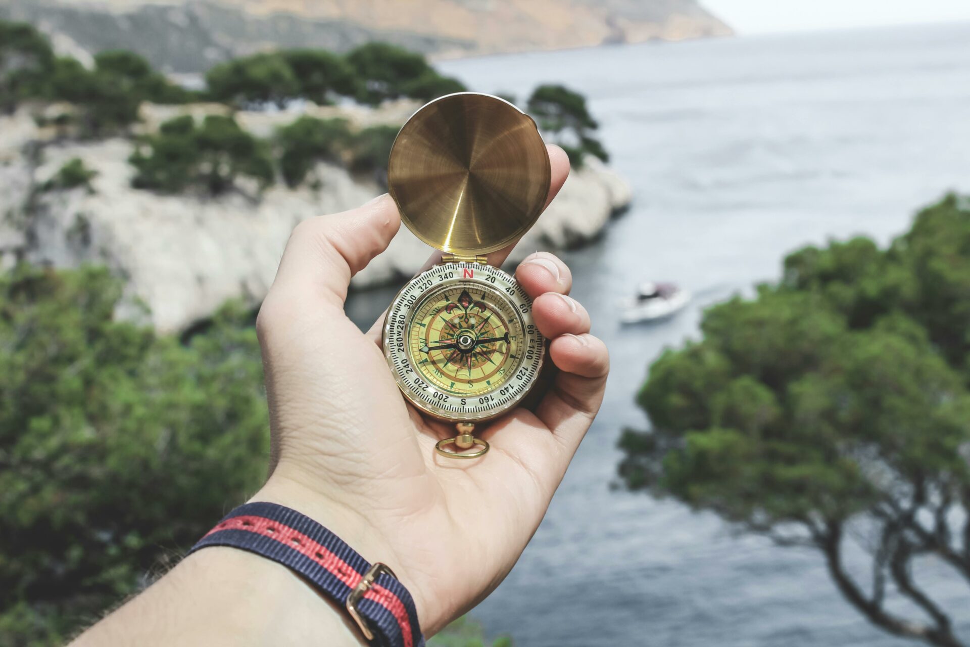 Hand holding a compass, outdoors in nature