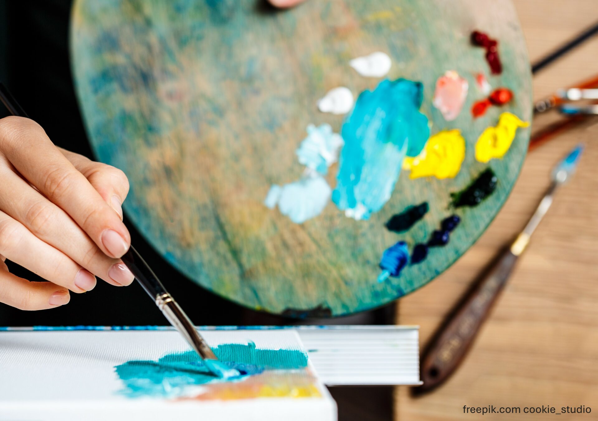 adult holding palette and paintbrush painting